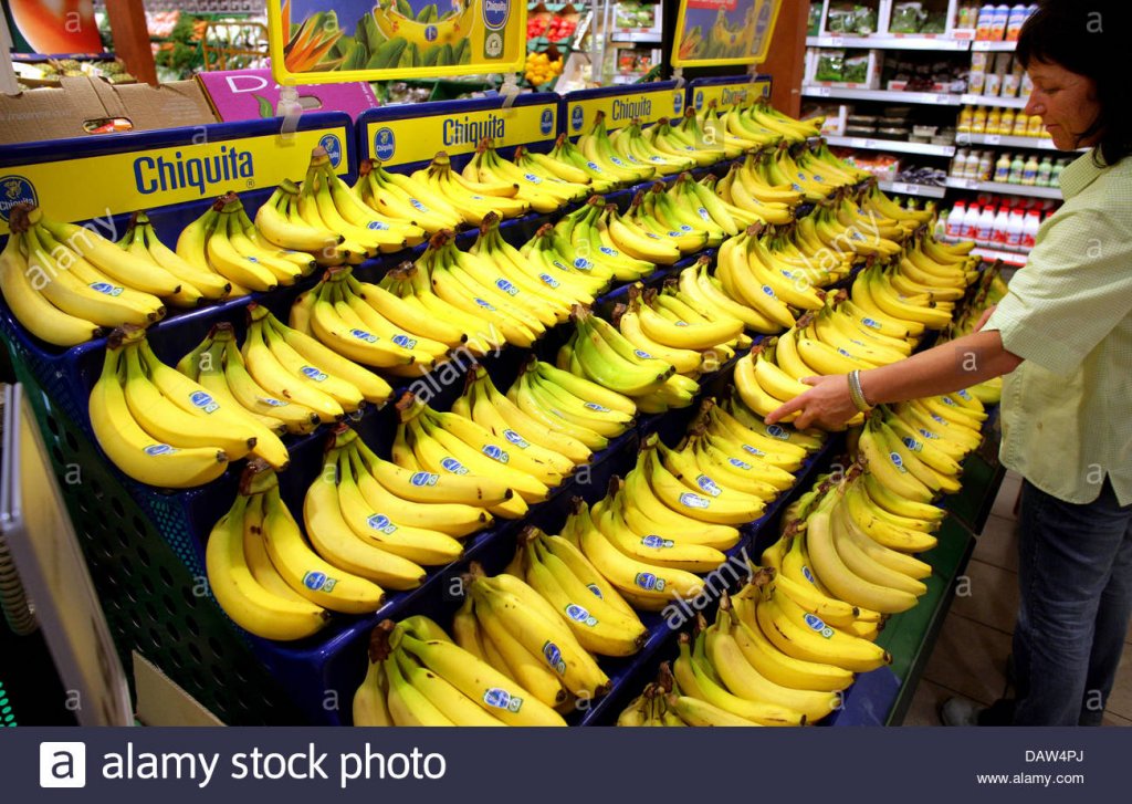 an-employee-arranges-bananas-at-a-remodeled-rewe-supermarket-store-DAW4PJ.jpg